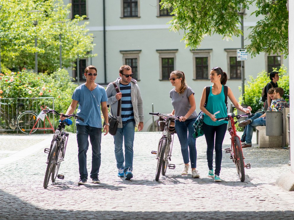 Studierende mit Fahrrädern auf dem Campus