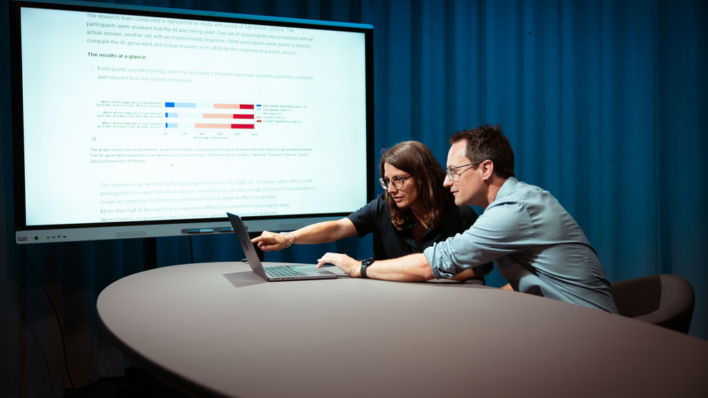 Professors Annette Hautli-Janisz and Steffen Herbold are pointing to a graph showing that the study participants overwhelmingly rated the imitated responses of the AI model as more authentic.