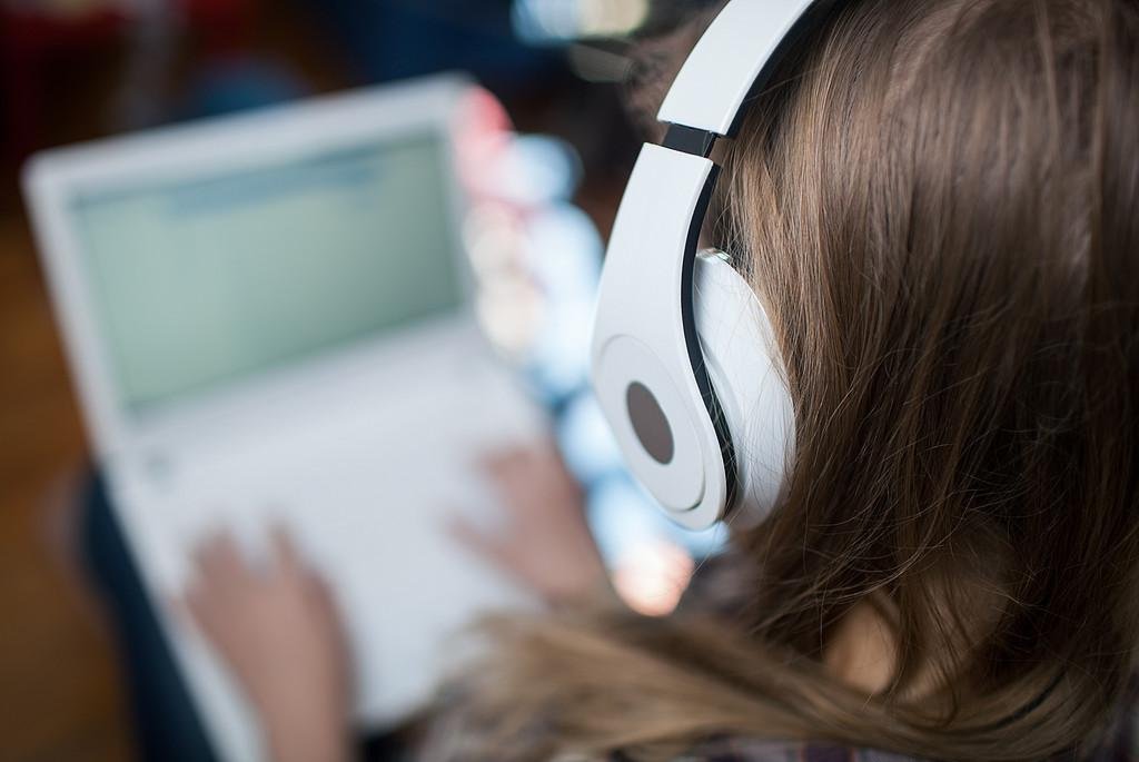 [Translate to Englisch:] Laptop und Person mit Kopfhörer