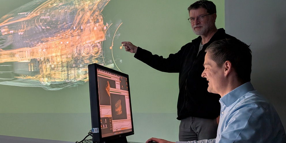 Prof. Dr. Tomas Sauer (stehend) und Prof. Dr. Christoph Heinzl demonstrieren die Visualisierung eines großen industriellen CT-Datensatzes in einer dreidimensionalen Darstellung.