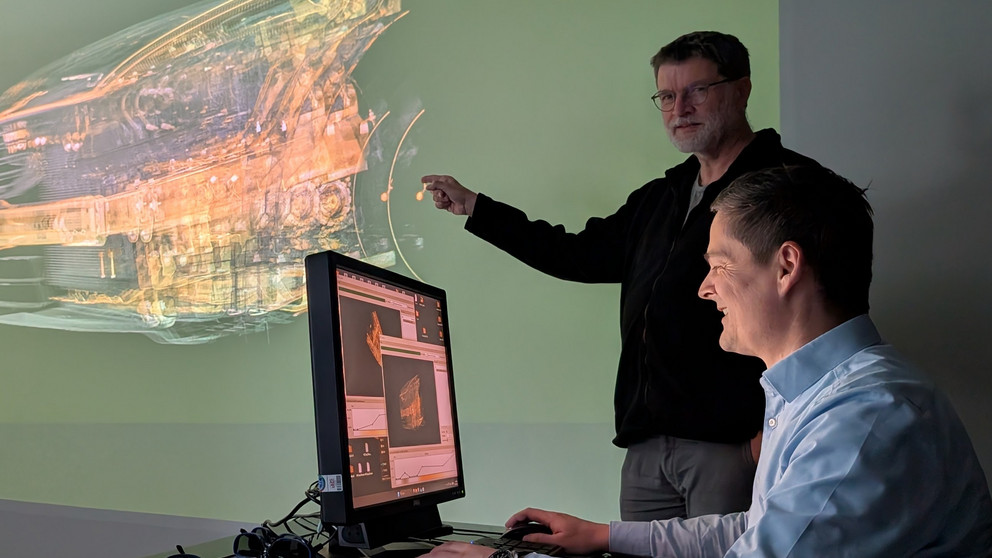 Prof. Dr. Tomas Sauer (stehend) und Prof. Dr. Christoph Heinzl demonstrieren die Visualisierung eines großen industriellen CT-Datensatzes in einer dreidimensionalen Darstellung.