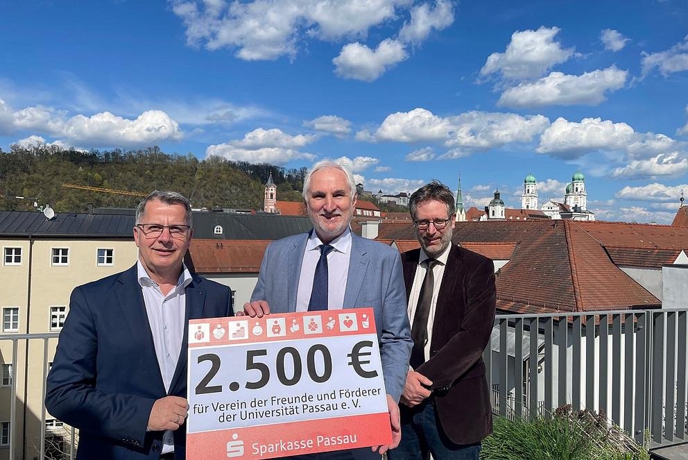 Christoph Helmschrott, Obmann des Sparkassenbezirksverbandes Niederbayern und Vorstandsvorsitzender der Sparkasse Passau (links), übergibt den Spendenscheck an Prof. Dr. Ulrich Bartosch, Präsident der Universität Passau, und Dr. Dr. Ansgar Grochtmann, Geschäftsführer des Vereins der Freunde und Förderer der Universität Passau e.V. (rechts), Foto: Universität Passau 