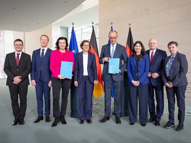Die EFI Kommission bei der &Uuml;bergabe des Jahresgutachtens 2026 an Bundeskanzler Friedrich Merz: Guido B&uuml;nstorf (v.l.), Joachim Henkel, Dorothee B&auml;r, Irene Bertschek, Friedrich Merz, Carolin H&auml;ussler, Christoph M. Schmidt, Friederike Welter. Foto: Linda K&ouml;hler-Sandring