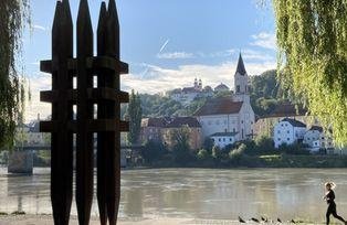 [Translate to Tschechisch:] Aufnahme der Skulptur mit Blickrichtung Inn, im Hintergrund die Innstadt mit St. Gertraud und Mariahilfkirche