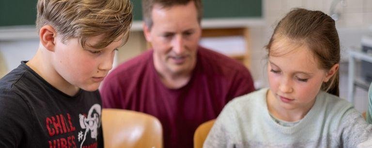 Junge und Mädchen sitzen während der Teilnahme am Mathezirkel an einem Tisch