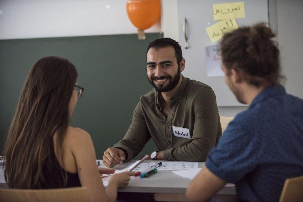 Lächelnder Wissenschaftler sitzt vor zwei Studierenden