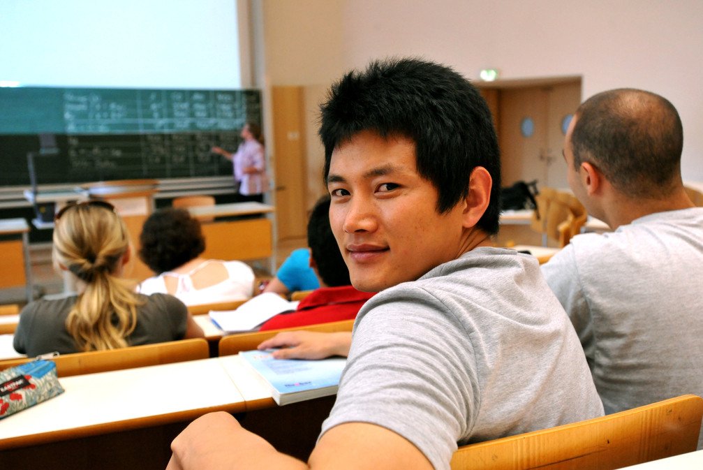 Student mit Blick zur Kamera sitzt im Audimax.