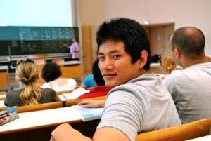 Student mit Blick zur Kamera sitzt im Audimax.