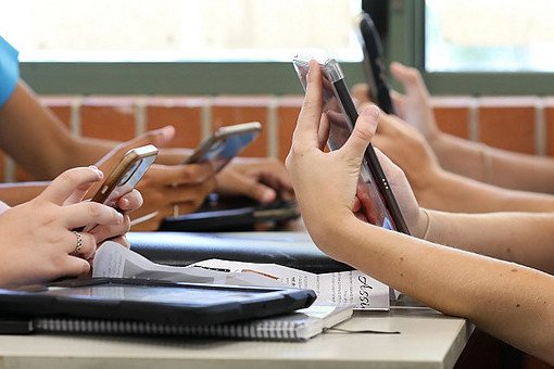 Ein Tisch mit Schülern, die Smartphones in der Hand halten