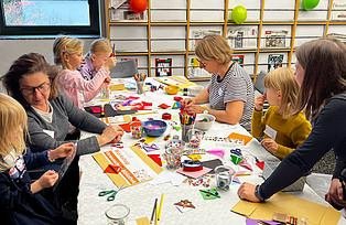 An einem großem Tisch basteln Kinder und Workshopleitungen zusammen "Bücherfresser".