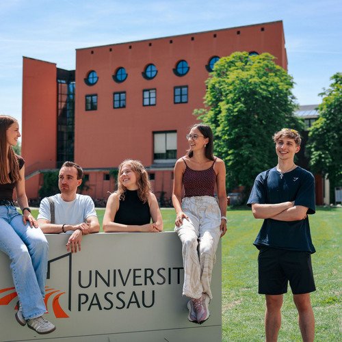 Studierende vor dem Campuslogo der Universit&auml;t Passau; Foto: Universit&auml;t Passau.