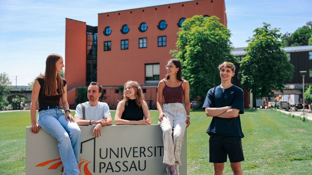 Studierende vor dem Campuslogo der Universit&auml;t Passau; Foto: Universit&auml;t Passau.