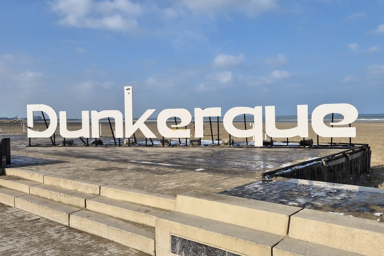 Gro&szlig;es Dunkerque-Schild an einer Strandpromenade.