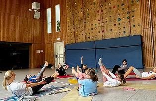 Die Kinder machen die Yogaposition "Navasana", auch das Boot genannt.