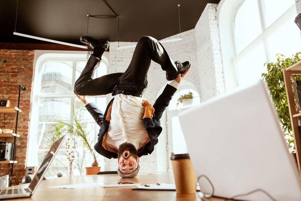 Junger Mann in Breakdance Bewegung auf einem Schreibtisch.