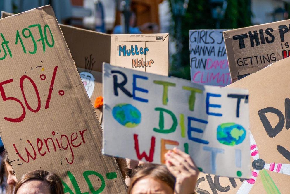 Demonstrierende auf einer Fridays-for-Future-Demonstration halten bunte Schilder für den Klimawandel hoch.