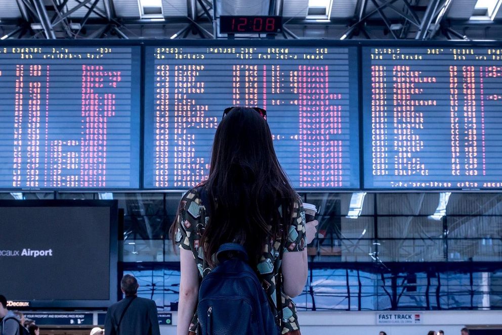 Frau steht vor Anzeigetafel am Flughafen