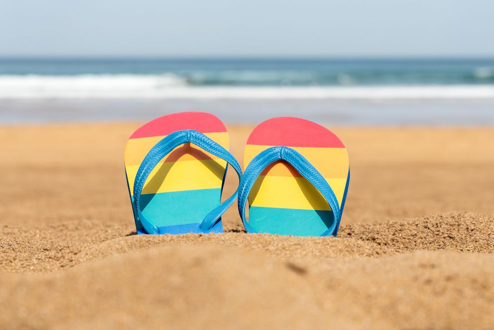Flip Flops in Regenbogenfarben am Strand an einem Sommertag