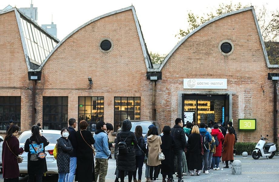 Menschen stehen in einer langen Schlange vor einem Gebäude an