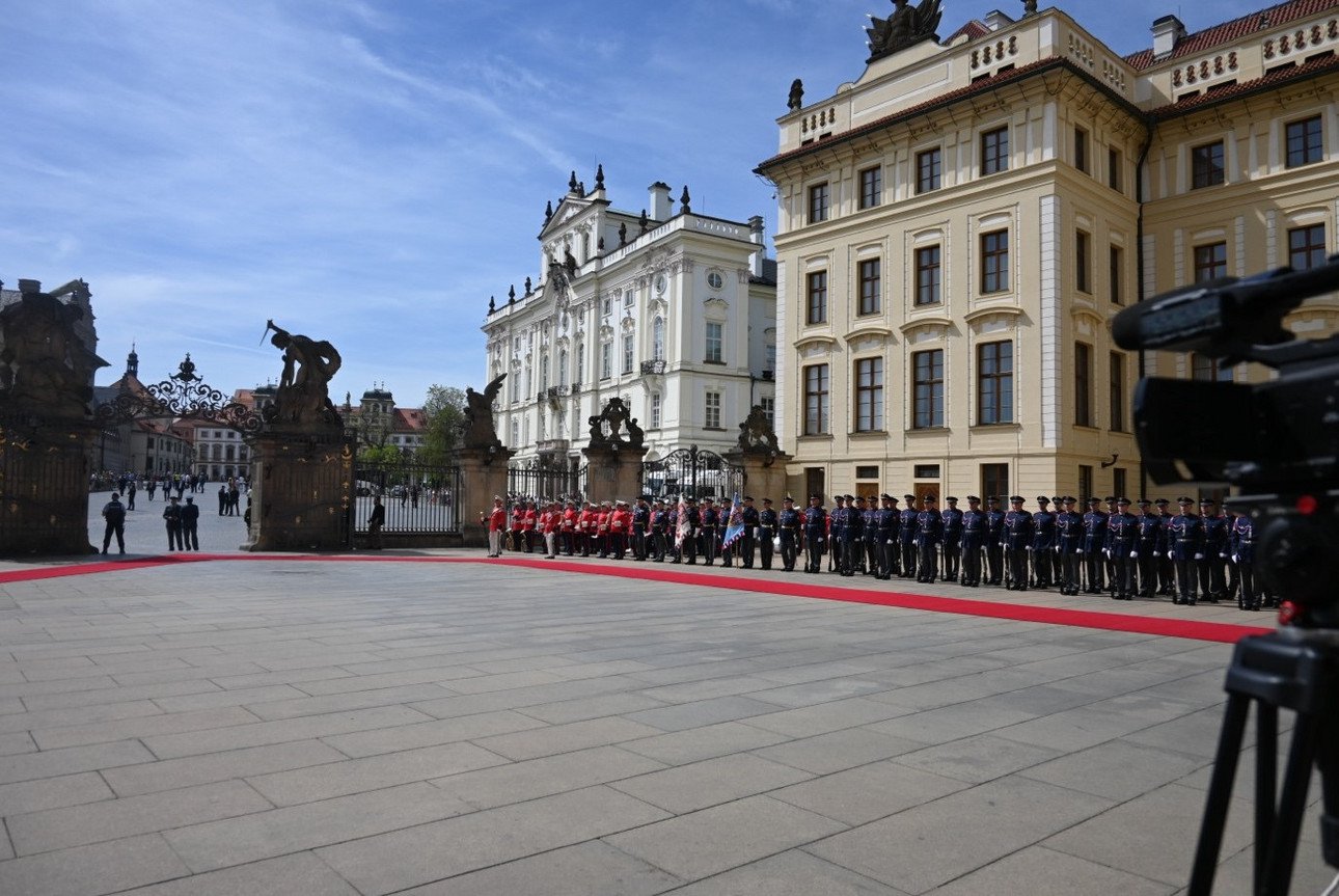 Staatsbesuch der deutschen Bundespr&auml;sidenten Frank-Walter Steinmeier in Prag. Zu sehen sind ein eingez&auml;unter Vorplatz auf dem ein roter Teppich ausgerollt ist. Auf den Mauern sind unterschiedliche Figuren zu sehen. Rechts stehen Soldaten Spalier. Im Hintergrund sind zwei H&auml;user im Barock-Stil in wei&szlig; und beige zu sehen. Ganz rechts im Bild sieht man eine Kamera, die auf die Szenerie gerichtet ist.