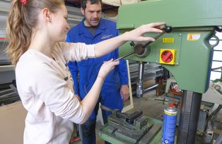 „Bohren ist cool“ – Schülerin Jana Beinbauer bearbeitet in der Betriebswerkstatt der Universität Passau Metall, Hausmeister Josef Stangl hilft.