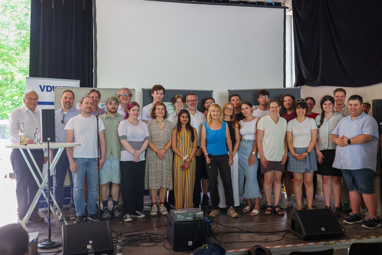 Gruppenfoto auf der B&uuml;hne des Kulturtransports der Teilnehmer der Veranstaltung "Grenzen &uuml;berwinden". Neben den Studierenden sind der Ehrenvorsitzende des BUND, Prof. Dr. Hubert Weiger, Dr. Philipp Blom und Dr. Maria Reinisch von der Vereinigung deutscher Wissenschaftler zu sehen.