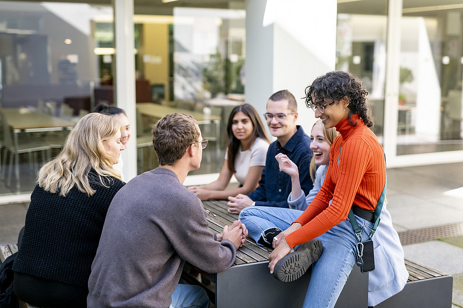 Studierende sitzen auf Bank vor ZMK Foto: Universität Passau