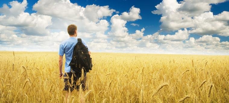 Rückenansicht eines Studenten mit Rucksack und Blick auf den Horizont.