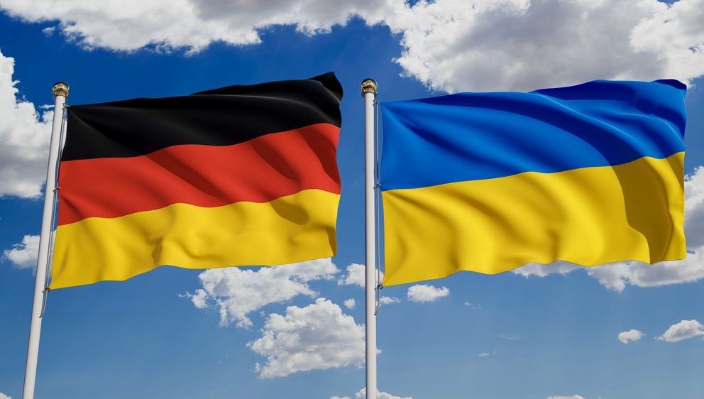 Die deutsche und die ukrainische Flagge vor blauem Himmel.