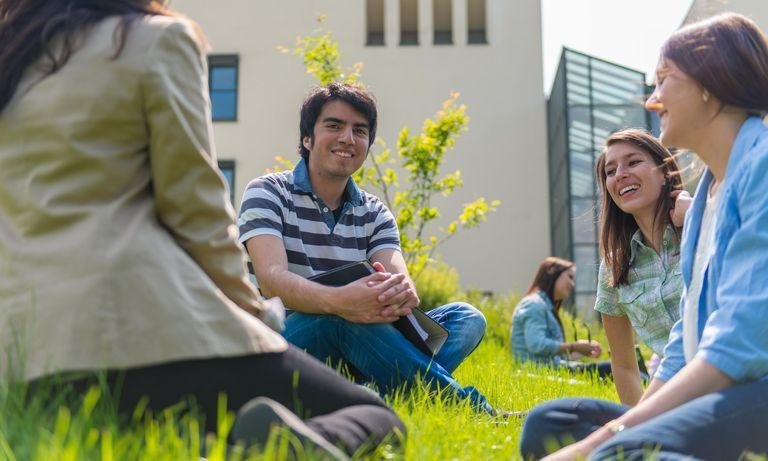 Studierende sitzen auf der Wiese vor der Fakultät für Informatik und Mathematik