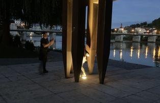 [Translate to Tschechisch:] Ansicht der Skulptur bei Dämmerung, im Hintergrund die Marienbrücke