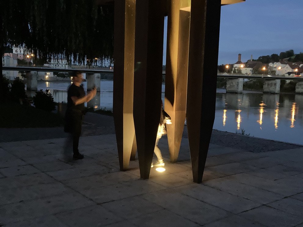 Ansicht der Skulptur bei D&auml;mmerung, im Hintergrund die Marienbr&uuml;cke