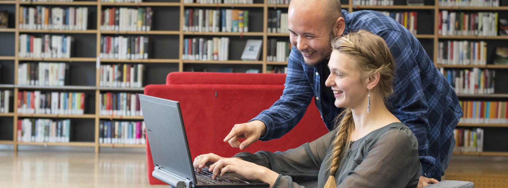 Zwei Personen sitzen vor einem PC