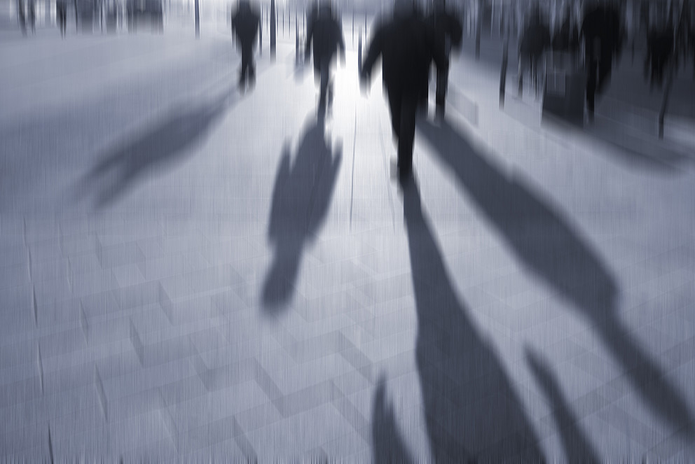 Verschwommenes Bild in Schwarz-Weiß von Menschen, die über einen Platz in einer Stadt eilen. Symbolbild: Colourbox 