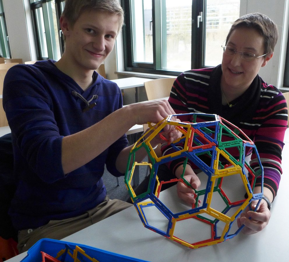 Ein Fu&szlig;ball ist auch nur Geometrie: Prof. Dr. Brigitte Forster-Heinlein zeigt Christoph P&ouml;hn (Gymnasium Zwiesel), wie man ihn aus F&uuml;nf- und Sechsecken konstruier (Bildquelle: Universit&auml;t Passau)