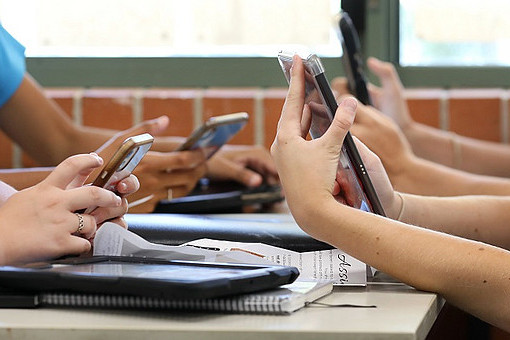 Ein Tisch mit Schülern, die Smartphones in der Hand halten