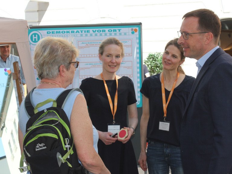Mit Passantinnen und Passanten im Gespr&auml;ch &uuml;ber Demokratie: (v.r.) Universit&auml;tspr&auml;sident Prof. Dr. Jan Hendrik Schumann, Dr. Linda v. Keyserlingk-Rehbein (Gesch&auml;ftsf&uuml;hrung Labor f&uuml;r Demokratiebildung) und Prof. Dr. Inken Heldt (Leitung Labor f&uuml;r Demokratiebildung / Lehrstuhl f&uuml;r das Politische System der Bundesrepublik und Politische Bildung); Foto: Jonas Dilger
