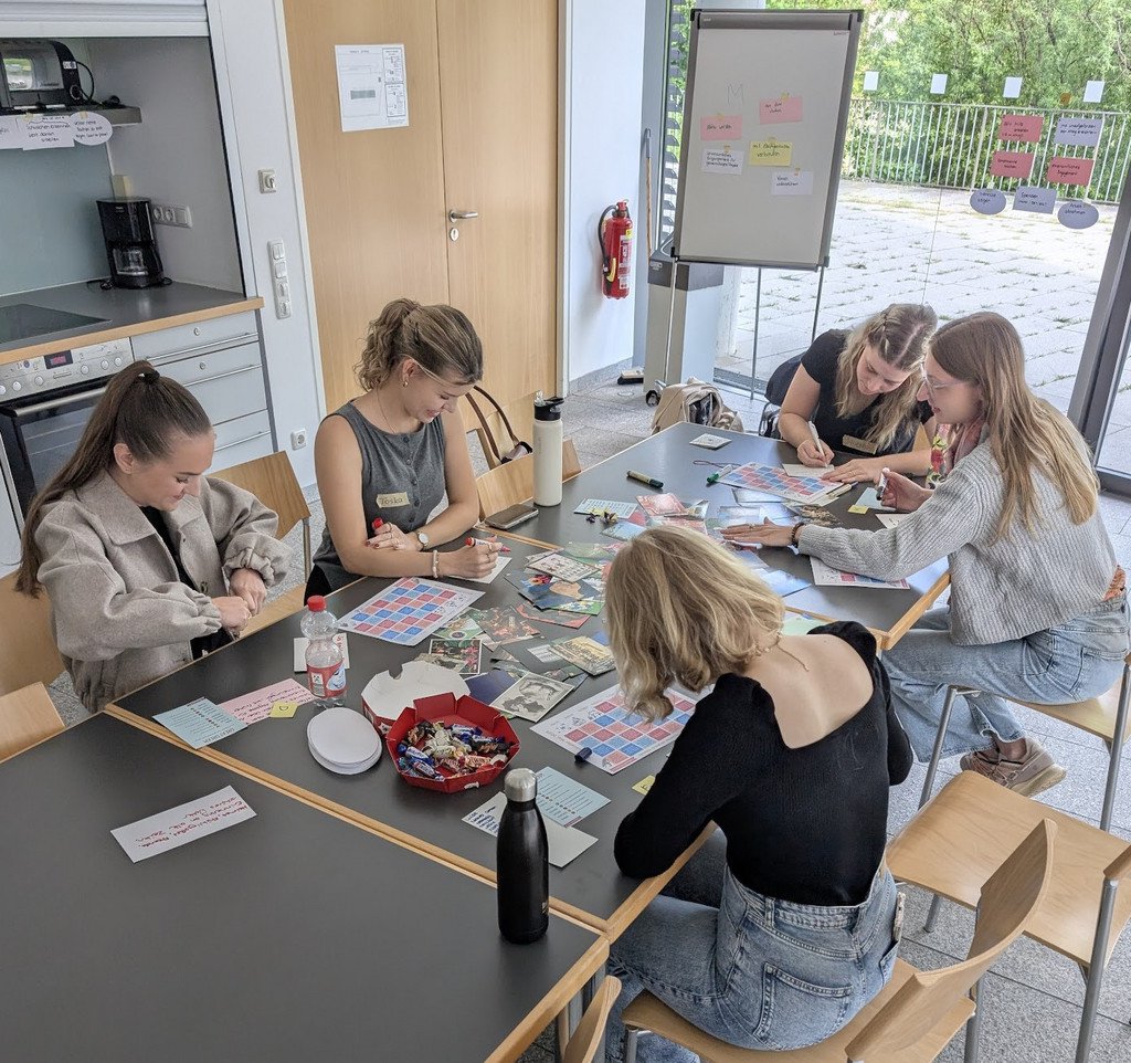 Eine Gruppe von Stipendiatinnen des Deutschlandstipendiums, welche an einem Tisch sitzen und gemeinsam Themen im Workshop "Action for Happiness" ausarbeiten.
