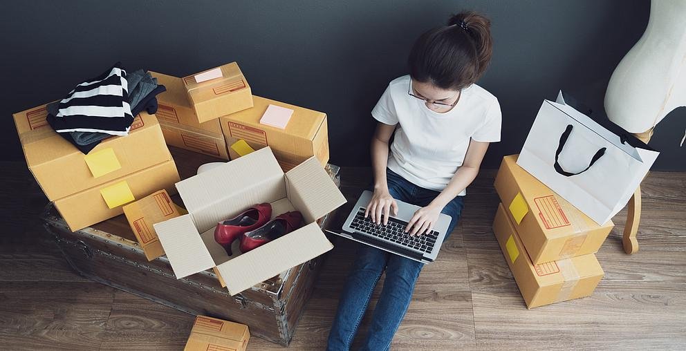 Top view of women working laptop computer from home on wooden floor with postal parcel, Selling online ideas concept Versandkartons