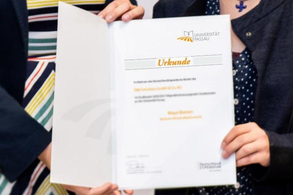 Förderer und Stipendiatin halten eine Urkunde Förderer und Stipendiatin halten eine Urkunde