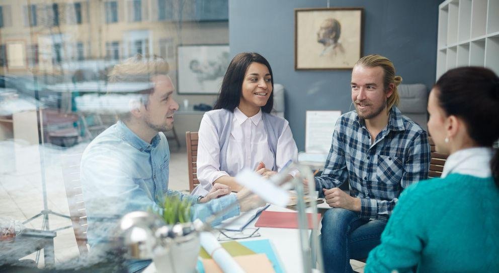 Vier junge Menschen sitzen um einen Tisch und unterhalten sich