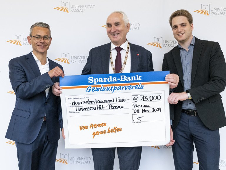 Michael Gruber, Vorstandsvorsitzender der Sparda-Bank Ostbayern eG (li), übergab gemeinsam mit Stephan Brandler, Leiter der Sparda-Bank-Filiale Passau (re) den Spendenscheck an Universitätspräsident Prof. Dr. Ulrich Bartosch (Mitte); Foto: Universität Passau