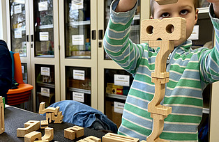 Ein Kind stapelt Zahlen aus Holz übereinander.