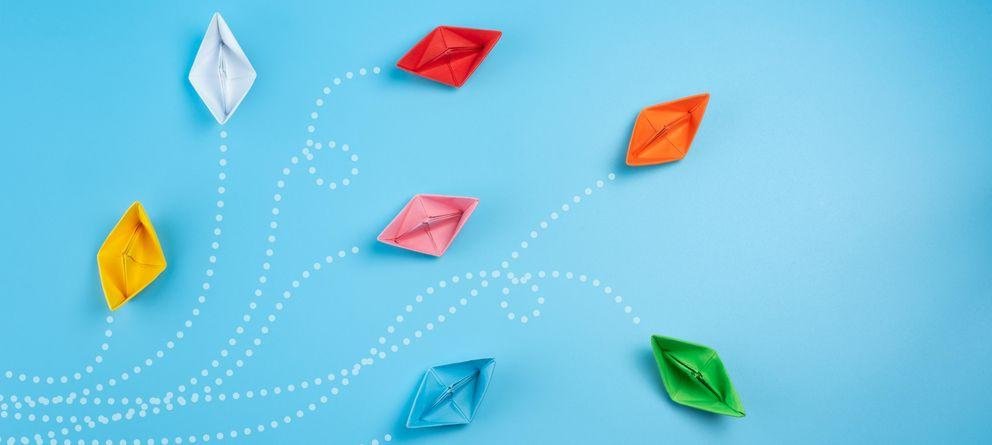 bunte Papierschiffchen bunte Papierschiffchen vor blauem Hintergrund