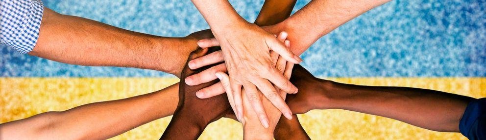 Ukraine people putting their hands together over the national fl Menschen reichen sich über der ukrainischen Flagge die Hände