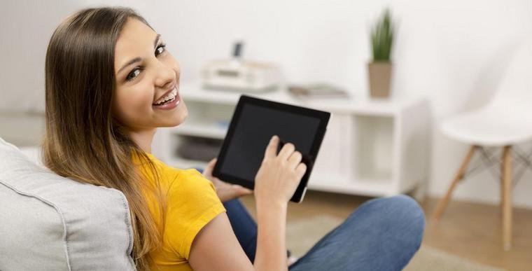 Studieninteressierte mit Tablet auf der Couch, die sich gerade bewirbt
