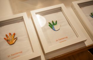 Auszeichnung (eine bunte Hand in einem Bilderrahmen) für die Workshop-Leitungen, gestaltet von der Unikinderkrippe