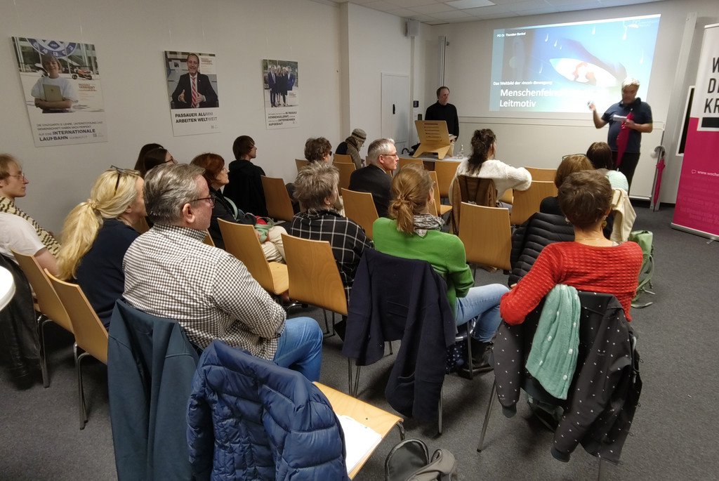 Bild von hinten aufs Publikum, vorne links Referent Dr. Thorsten Benkel bei Uni live - Vortrag am 29.10.2025