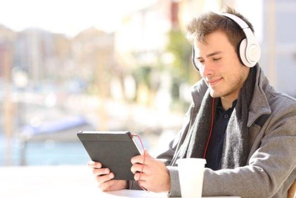 Junger Mann mit Kopfhörern und Tablet