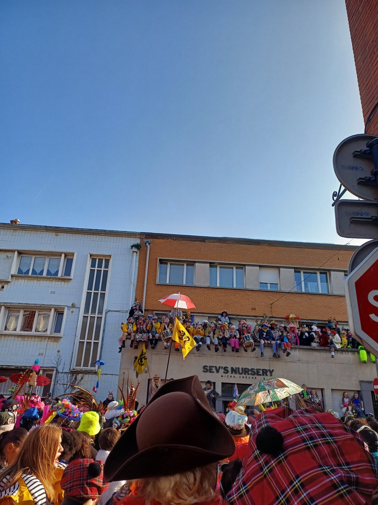 Buntes Karnevalstreiben in Dunkerque mit verkleideten Menschen auf der Stra&szlig;e und auf dem Balkon.